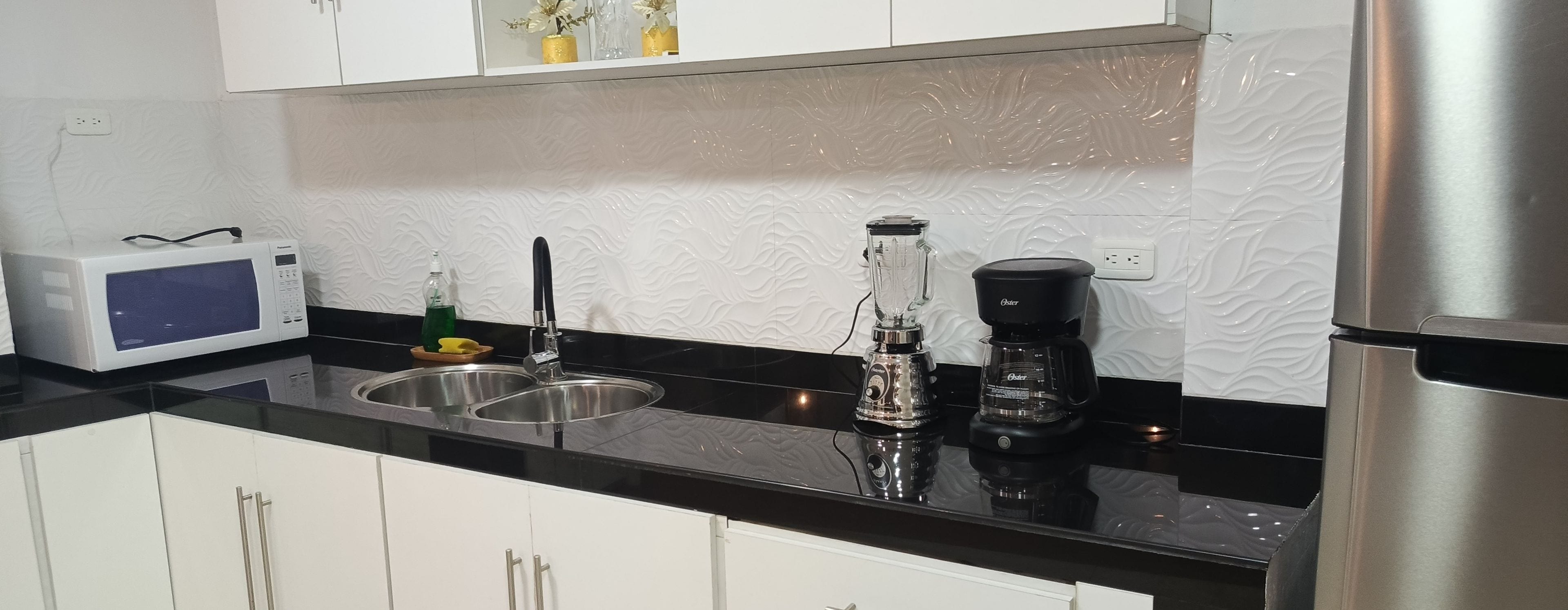 A kitchen with a microwave, sink, and coffee maker.