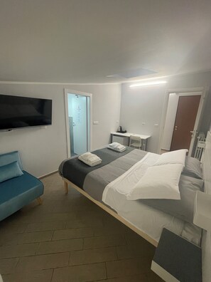 Een hotelkamer met een bed, een aan de muur bevestigde televisie, een bureau en een stoel.