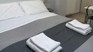 A modern hotel room with a neatly made bed, a chair, and a radiator. - Central Suite 57 (Turin)