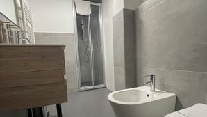 A modern bathroom with a wooden vanity, a freestanding bathtub, and a toilet. - Central Suite 57 (Turin)