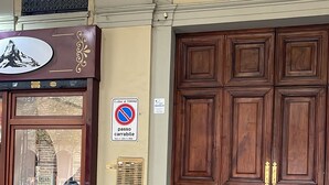 A building facade with a large wooden door, a sign indicating a no parking zone, and a window with a view of the street. - Central Suite 57 (Turin)