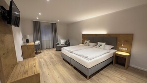 A modern hotel room with a large bed, two bedside tables, a desk, a chair, and a TV mounted on the wall. - Hotel Gasthof zur Post Benediktbeuern (Benediktbeuern)