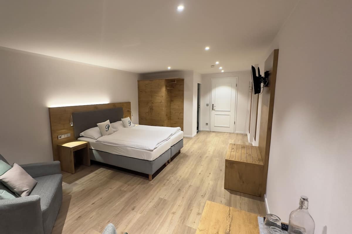 A modern bedroom with a bed, bedside table, and a grey sofa.