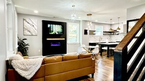 A modern living room with a brown sofa, a flat-screen TV, and a fireplace. - Epic Retreat at Mystic Falls-5 bd 3.5 BA-1 Mile from the Square & Clocktower (Covington)