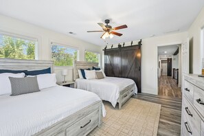 A bedroom with two beds, a ceiling fan, and a view of the outdoors. - 11 East Wind ~ Ocean Front Stunner! (Hilton Head Island)
