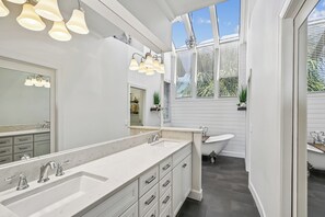 A bathroom with a large mirror, two sinks, a bathtub, and a window with blinds. - 11 East Wind ~ Ocean Front Stunner! (Hilton Head Island)