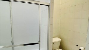 A bathroom with a shower enclosure, toilet, and a roll of toilet paper on the wall. - Charming 2-bedroom apartment in delightful New York with WiFi, AC (New York)