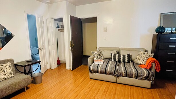 A living room with a sofa, a coffee table, and a TV stand. There is a door leading to another room and a staircase. - Charming 2-bedroom apartment in delightful New York with WiFi, AC (New York)