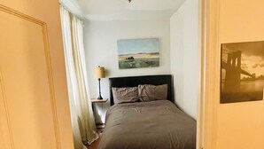 A bedroom with a bed, a nightstand, a lamp, and a painting on the wall. - Charming 2-bedroom apartment in delightful New York with WiFi, AC (New York)