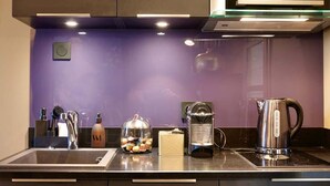 A modern kitchen with a built-in stove, a coffee maker, and a kettle on the counter.