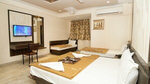 A hotel room with a large bed, a desk, a chair, a television, and a ceiling fan. - Hotel Sai Suraj Park (Rahata)