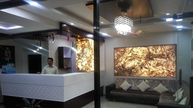 A reception area with a reception desk, a sofa, and a large abstract wall art piece. - Hotel Sai Suraj Park (Rahata)