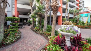 Een hotelentree met een pad omzoomd door palmbomen, een bloembed en een bord met daarop Grande Cayman Resort.