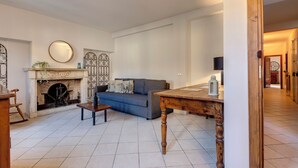 Un salon avec une cheminée, un canapé, une table basse et une table en bois.