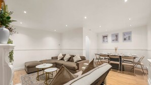A modern living room with a sectional sofa, a round dining table, and a bench. - Manchester - City Centre - Hot Tub - Free Private Parking - Sleeps 8 (Greater Manchester)