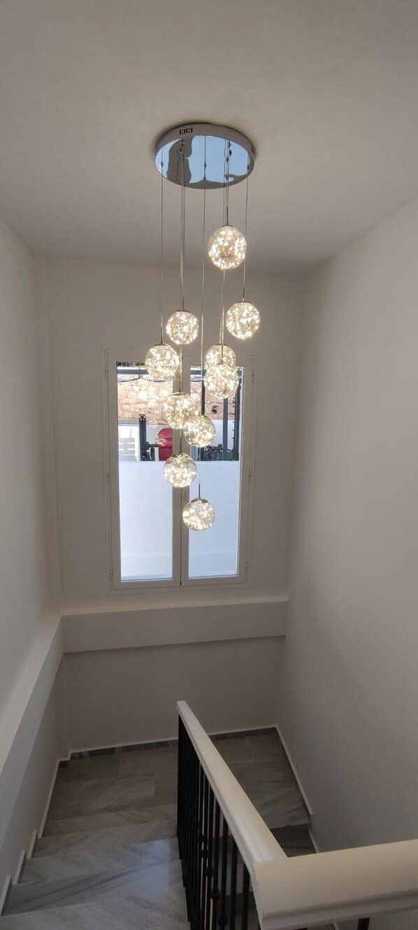 A staircase with a modern light fixture hanging from the ceiling.