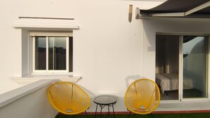 A modern building with a white exterior, a sliding glass door, and two yellow wicker chairs outside. - Marbella Oasis Villa With 6 Bedrooms (Marbella)
