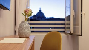 A room with a wooden table, a vase with a flower, and a view of a building with a dome. - MAIN - Duomo (Naples)