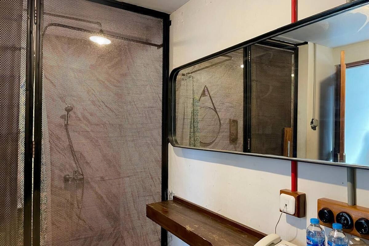 A hotel room with a wooden bench, a telephone, and a mirror.