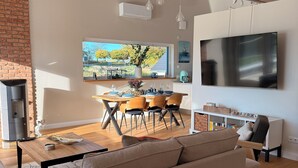 Ein modernes Wohnzimmer mit einer Couch, einem Essbereich mit Stühlen, einem Fernseher und einem Kamin.