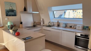 Eine moderne Küche mit einer zentralen Kochinsel, einem Einbauofen und einem Fenster mit Blick auf die Nachbarschaft.