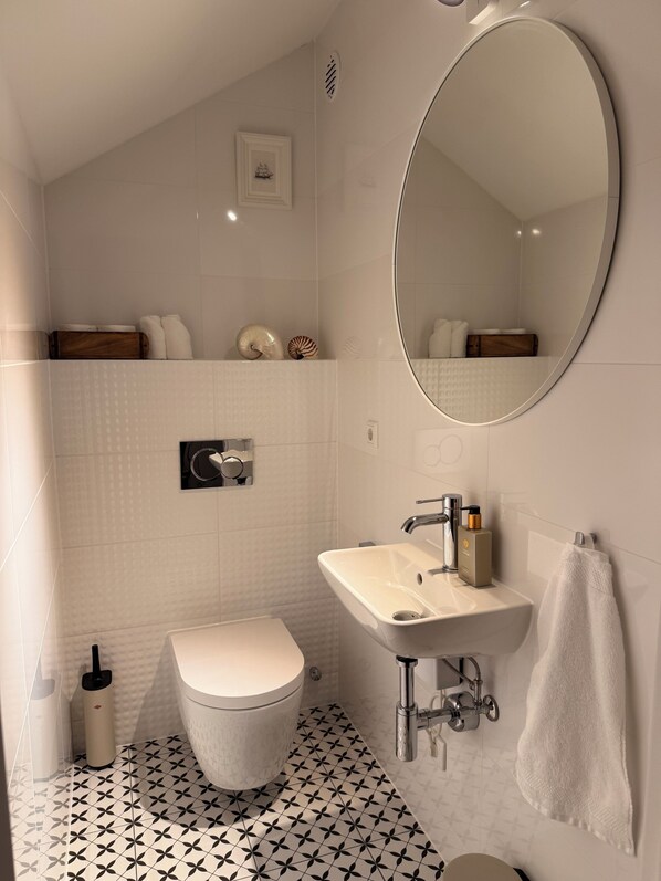 A modern bathroom with a toilet, sink, and mirror. - Vacation home on Lake Möhne - designer house with plenty of space for 6 people (Möhnesee)
