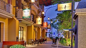 An indoor courtyard with outdoor seating, a Dolce Vita Coffee & Sweets sign, and a fountain. - Stylish Condo with Stunning View in Los Suenos (Herradura)