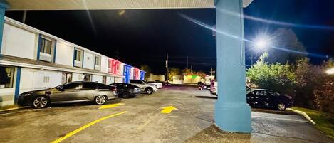 A parking lot with cars parked under a building with a blue pillar.