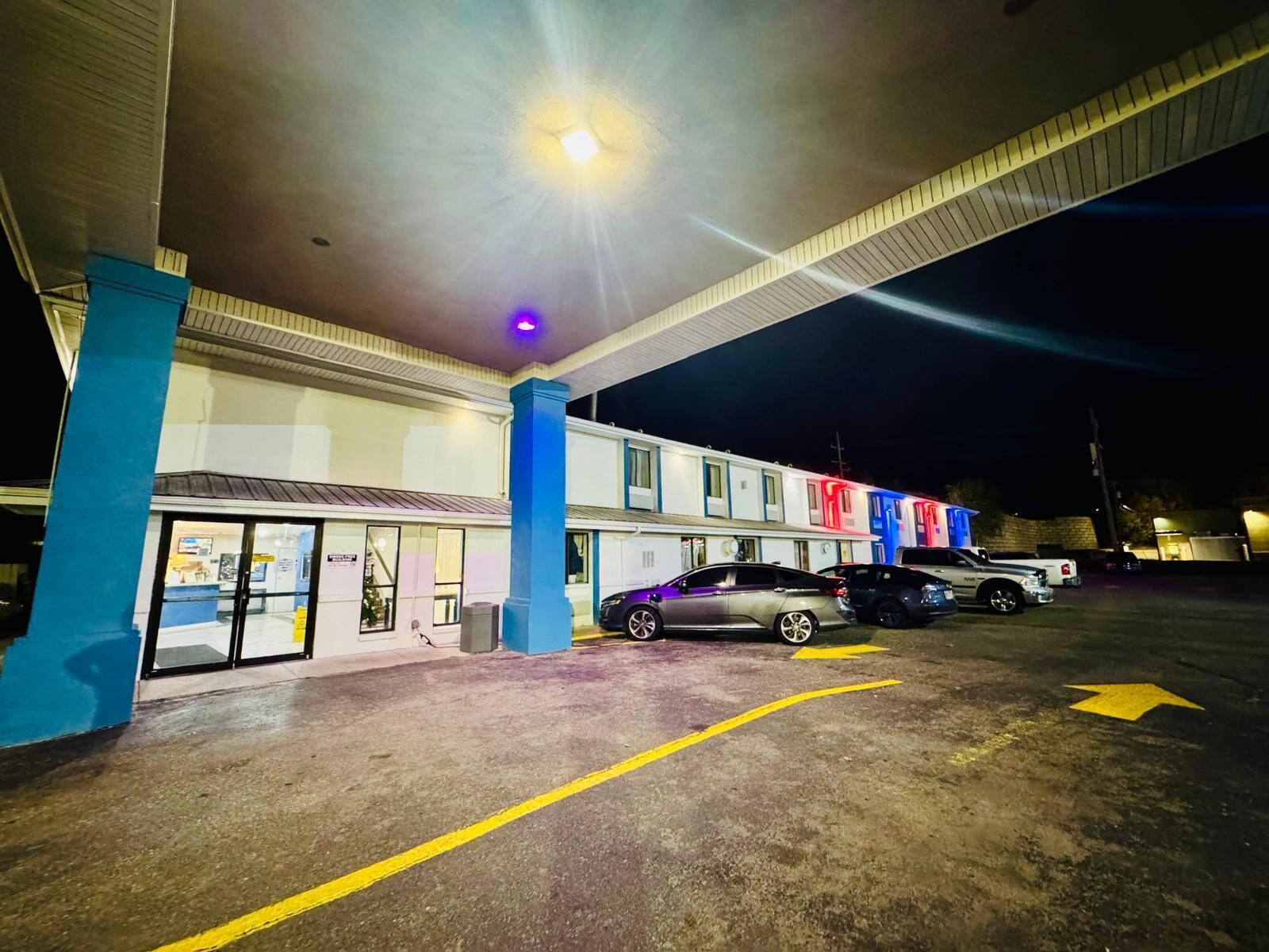 Ein Parkplatz mit einem Motelgebäude, Autos und einer blauen Säule.