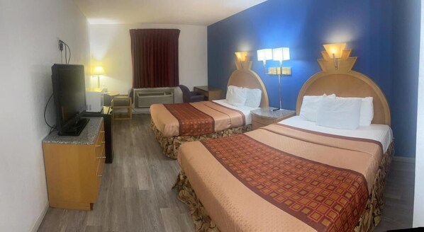 A hotel room with two beds, a TV, a desk, and a chair.