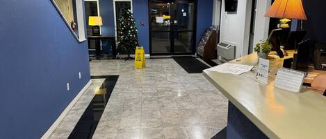 A hotel reception area with a Christmas tree, a reception desk, and an exit sign.