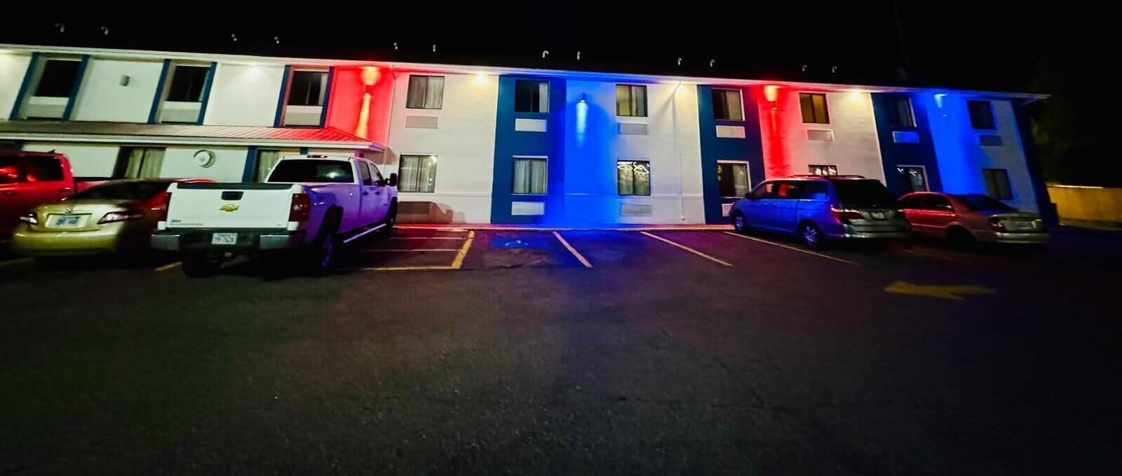 Un motel con un estacionamiento y varios automóviles estacionados.