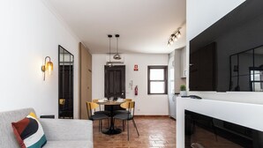 A modern living room with a sofa, a dining area with chairs and a table, and a fireplace. - Zinnia Villa, Tavira, Algarve (Tavira)