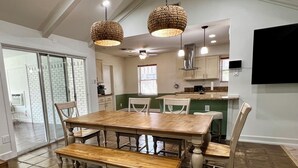 A dining area with a wooden table and chairs, a bench, and two hanging wicker lamps. - Big Heated Pool w Sunroom, Centrally-loc. Luxury in Houston, Billiards, Sleeps16 (Houston)