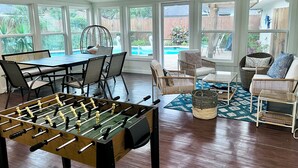 A spacious room with a foosball table, comfortable seating, large windows, and a view of a backyard. - Big Heated Pool w Sunroom, Centrally-loc. Luxury in Houston, Billiards, Sleeps16 (Houston)