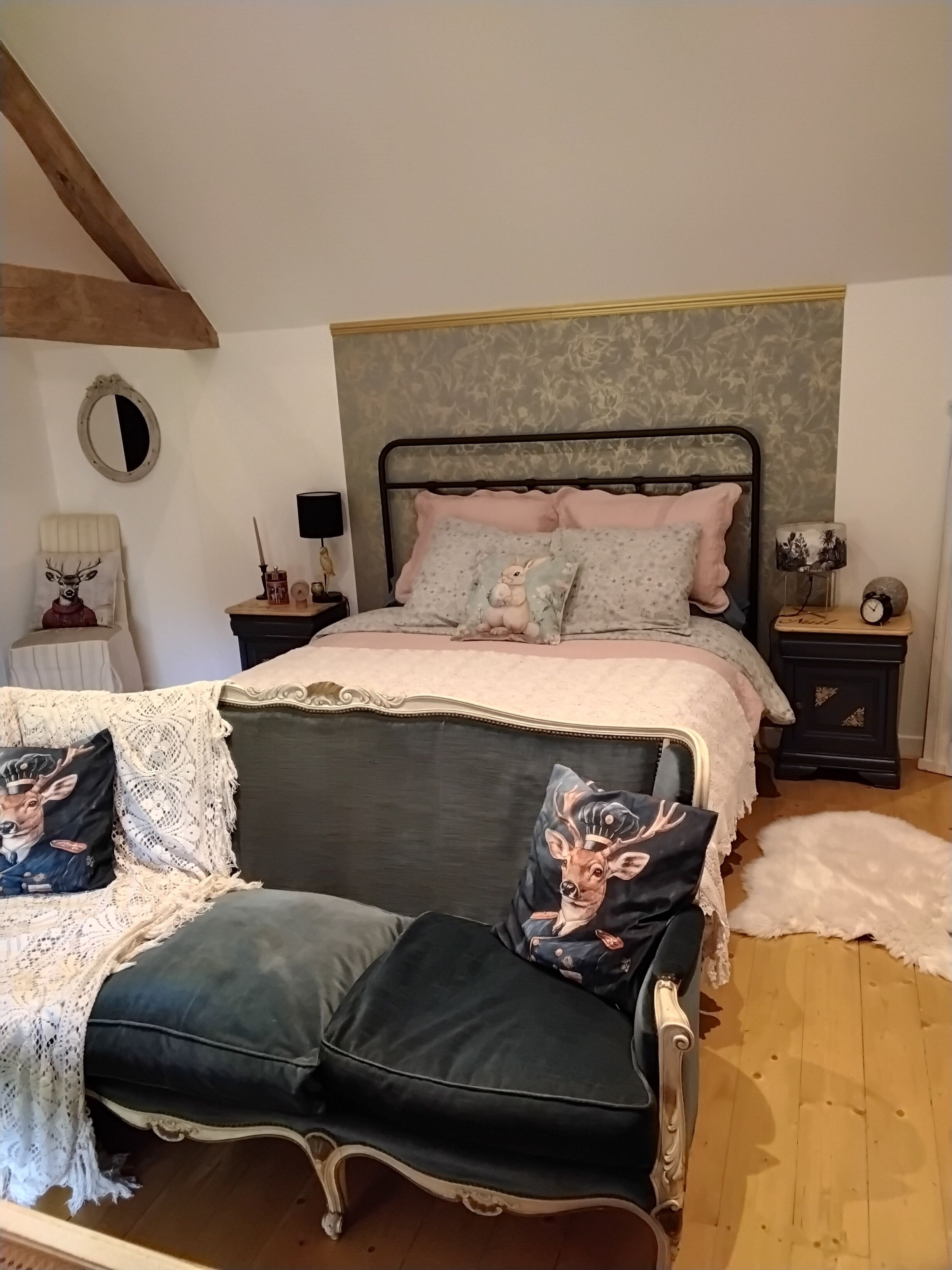 A bedroom with a bed, two nightstands, a chair, and a decorative mirror.