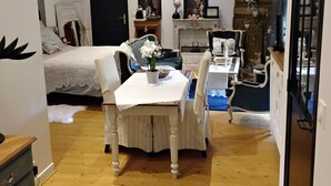 A cozy room with a bed, a dining table with chairs, a fireplace, and a large window. - Au petit bonheur de Séraphine (saint aubin)