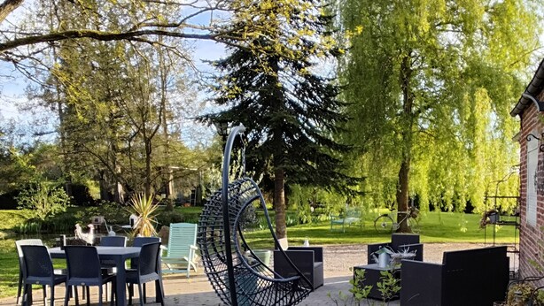 An outdoor patio with a dining area, a hanging chair, and potted plants. - Au petit bonheur de Séraphine (saint aubin)