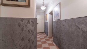 Un pasillo con paredes estampadas, suelo a cuadros y una araña.