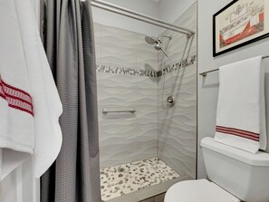 A modern bathroom with a shower, toilet, and a framed picture on the wall. - Superstition Springs Mesa (Mesa)