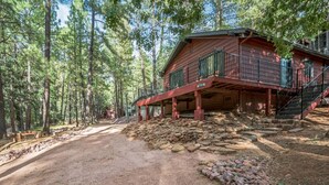 Une cabane avec une façade en bois, un balcon et un escalier menant à l’étage supérieur.
