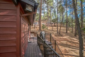 A wooden deck with a metal railing, a barbecue grill, and a small table and chair set.