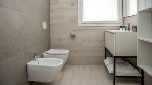 A modern bathroom with a bidet, toilet, and a vanity with a mirror. - CAMELOT APARTMENT RED3 (VERONA)