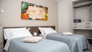 A hotel room with two beds, a large abstract painting on the wall, and a desk with a chair. - CAMELOT APARTMENT RED6 (VERONA)