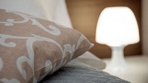 A close-up of a bed with a patterned pillow and a white bedside lamp. - CAMELOT APARTMENT RED6 (VERONA)