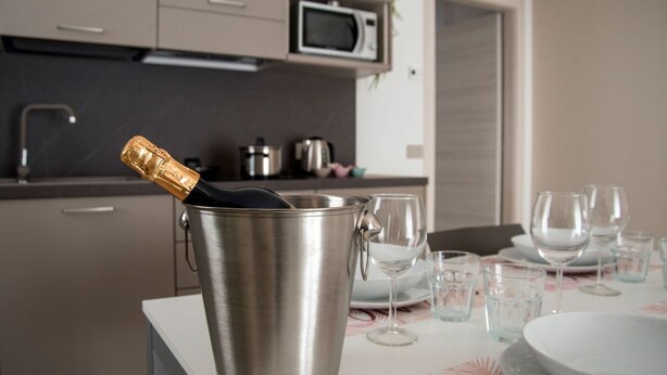 Eine Küche mit einem Edelstahl-Eimer, der eine Champagnerflasche, eine Mikrowelle und diverse Küchengeräte enthält.