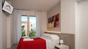 Ein Hotelzimmer mit Bett, Nachttisch, einem Bild und einem Fenster mit Vorhängen.