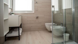 A modern bathroom with a wooden floor, a glass shower enclosure, a white sink, and a toilet. - CAMELOT APARTMENT RED4 (VERONA)