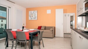 A modern apartment with a dining area, a sofa, and a kitchen. - CAMELOT APARTMENT RED8 (VERONA)
