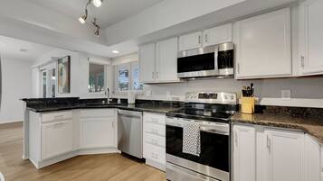 A modern kitchen with white cabinetry, stainless steel appliances, and a granite countertop.